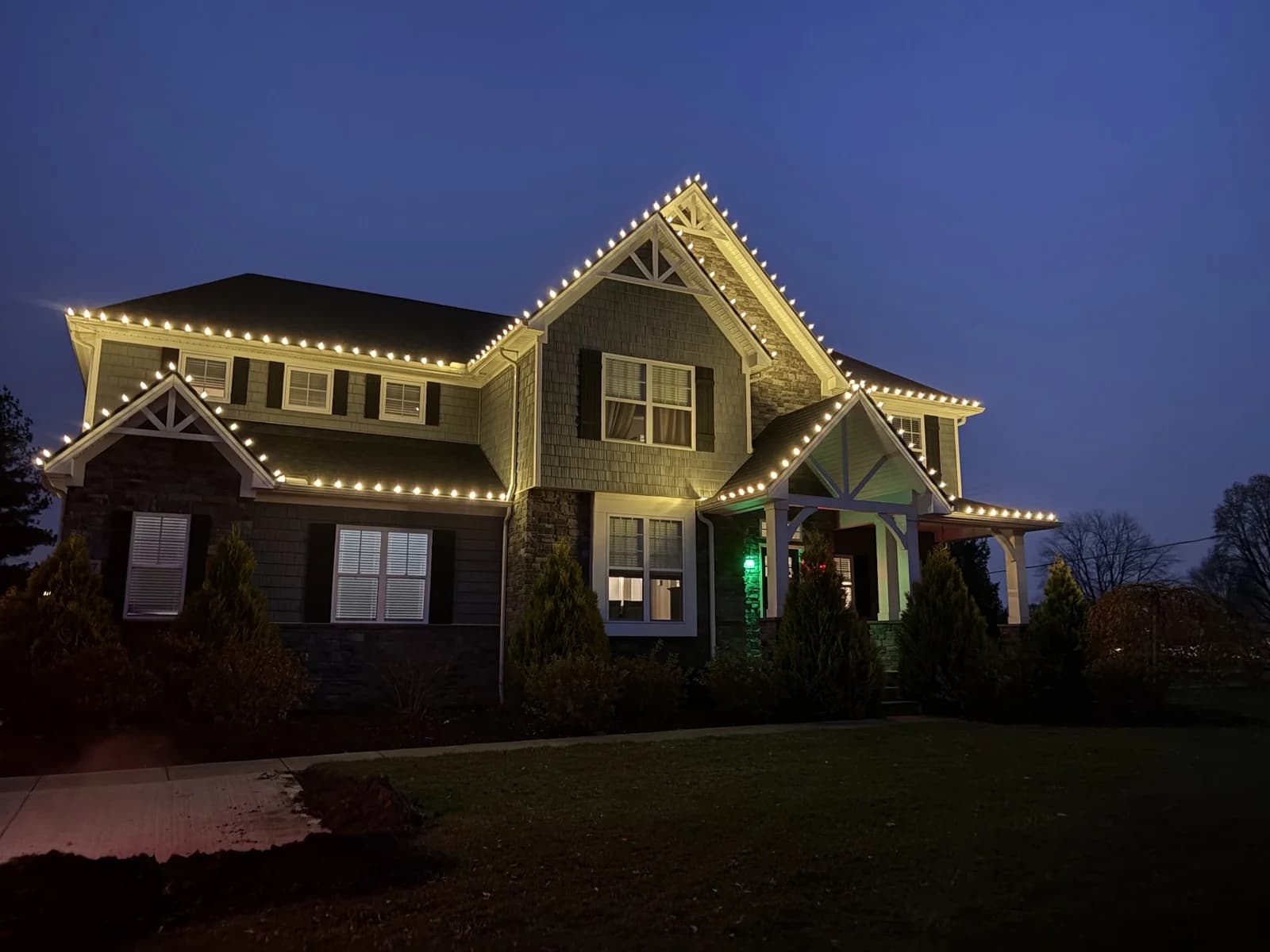 Warm roofline lights on a two-story home in Avon, installed by Shoreline