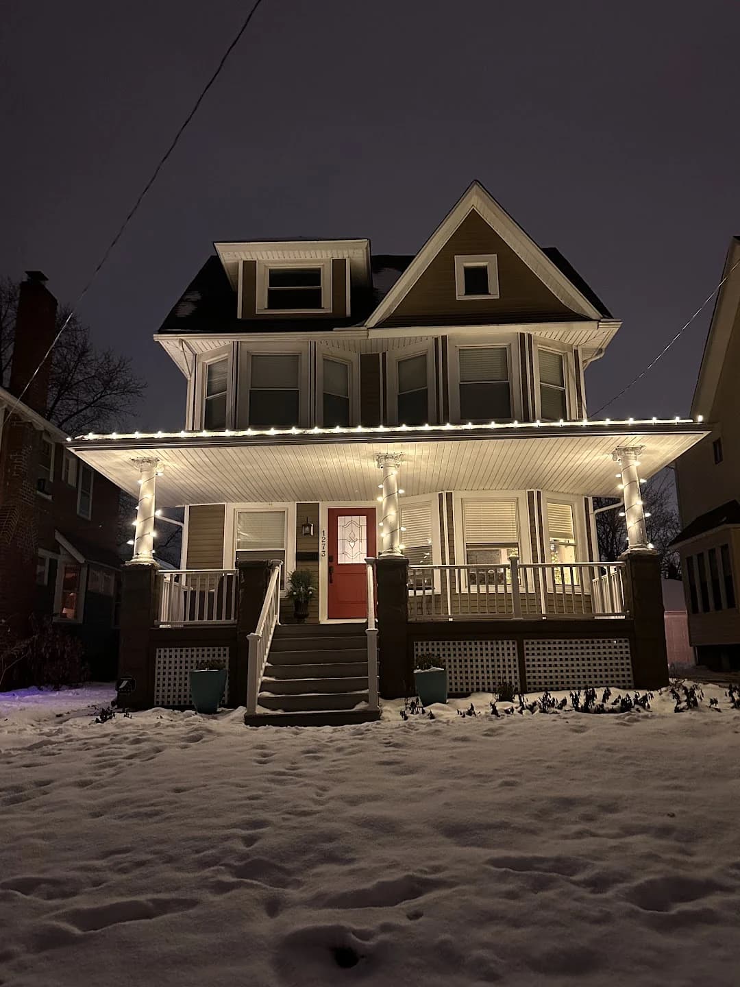 Warm lights along a home’s porch roof and columns in Lakewood, installed by Shoreline
