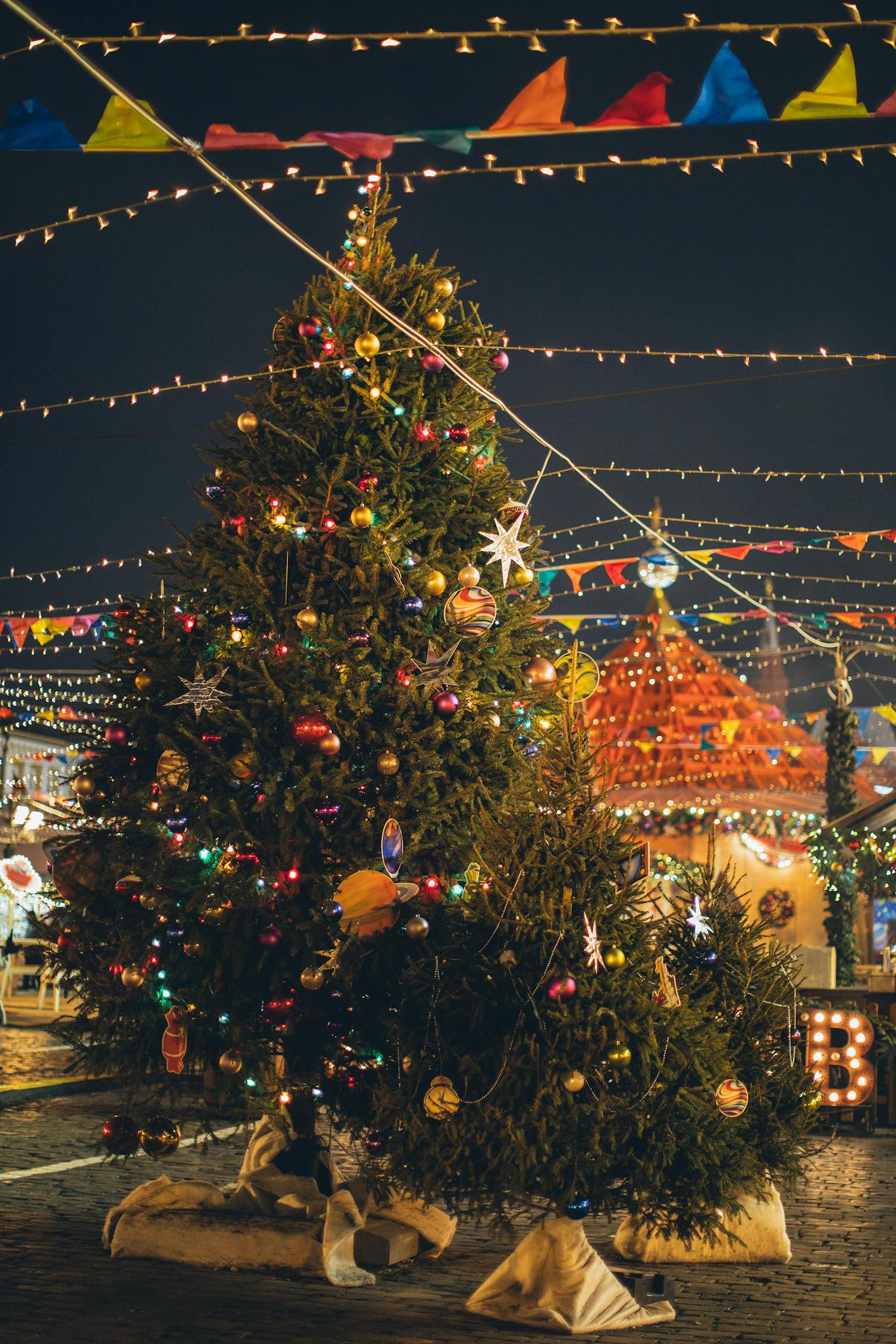 Colorful Christmas decorations light up a festive outdoor market with a beautifully adorned tree.
